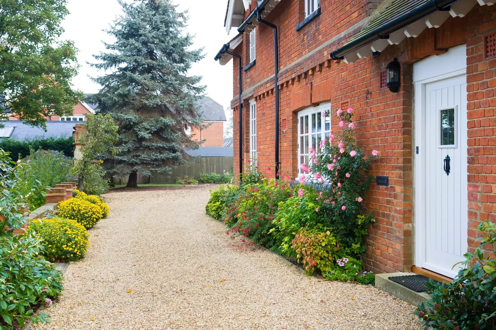 Bespoke red-brick home with gravel driveway and cottage garden by Claremont Build & Co